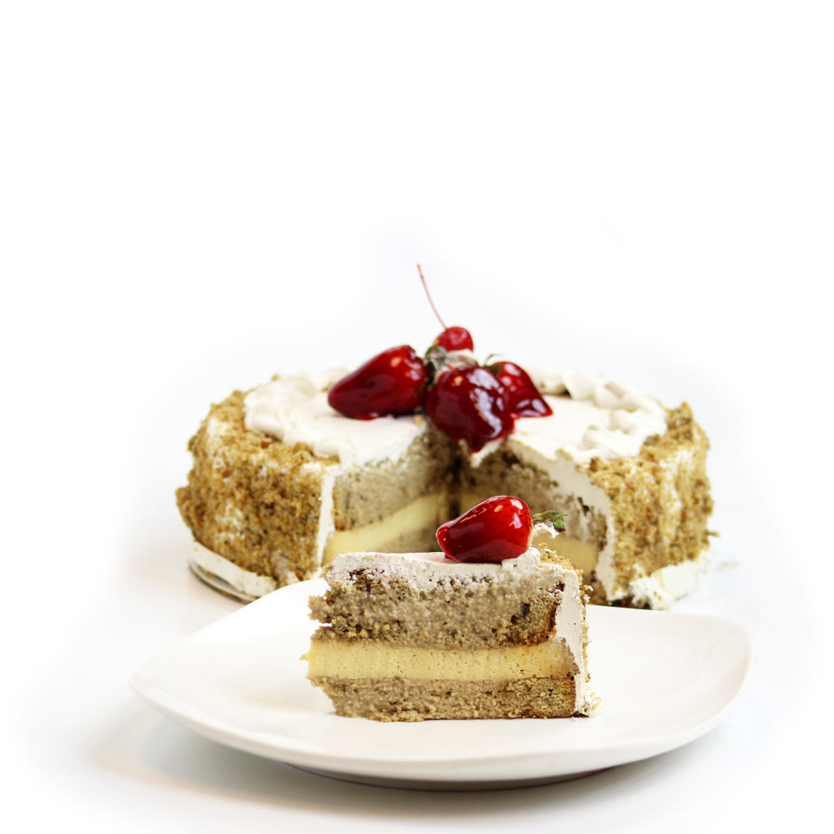 Tres leches cake topped with strawberries, with a slice served on a plate
